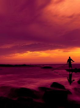 Silhouette of a person during a vibrant sunset on Kannur Beach, India.