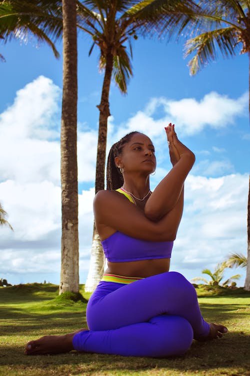 Low-Angle Shot of a Woman in Purple Activewear Sitting on Grass Field