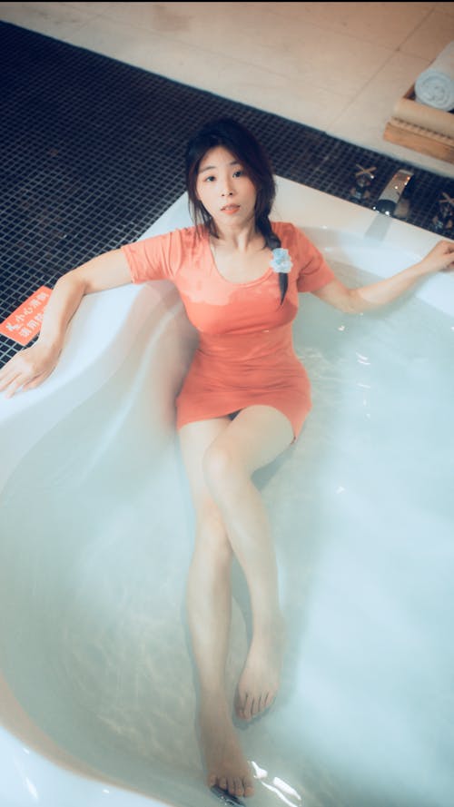 Woman Wearing a Dress Lying in a Bathtub 