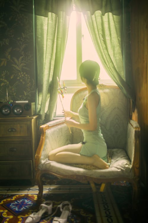 Woman Kneeling on an Armchair and Looking out the Window 