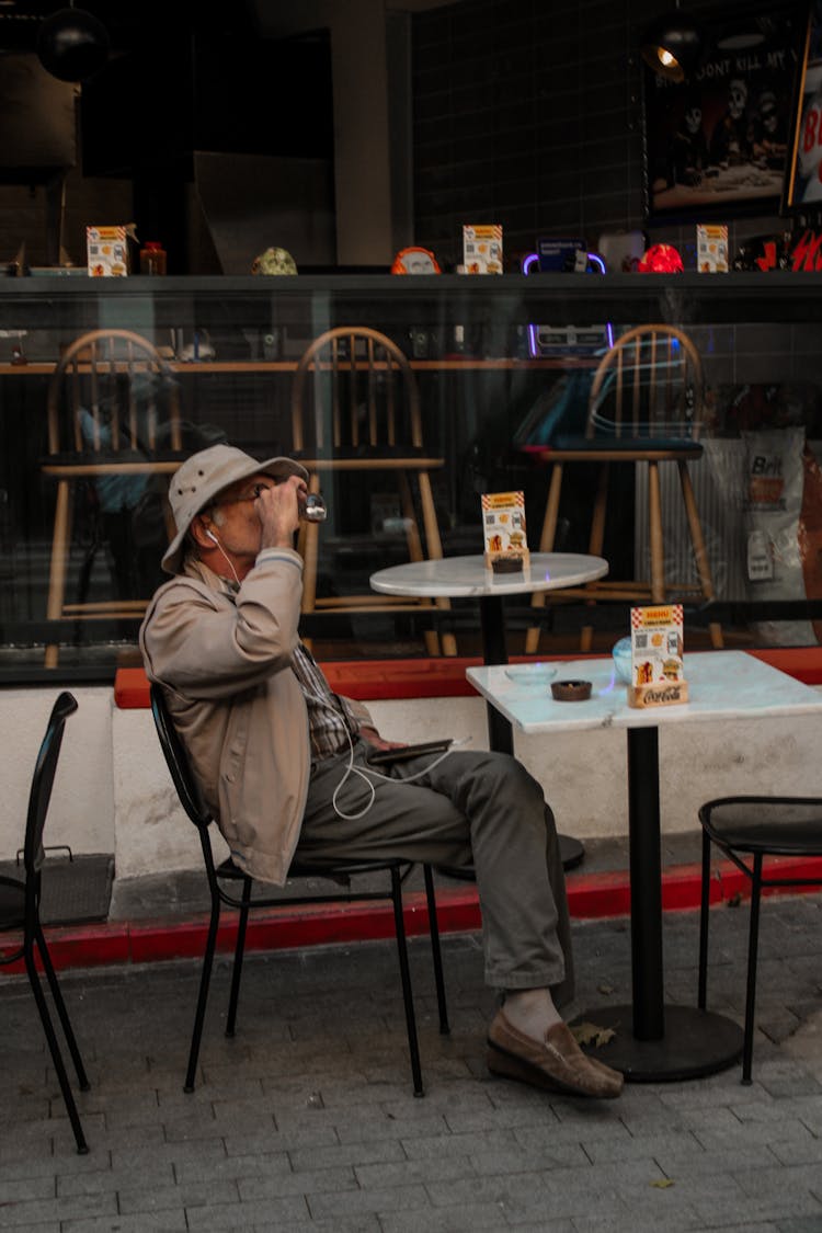 Old Man Sitting At Outdoor Cafe Table