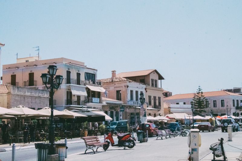 Busy resort street with cafés and shaded terraces on a sunny afternoon in Crete