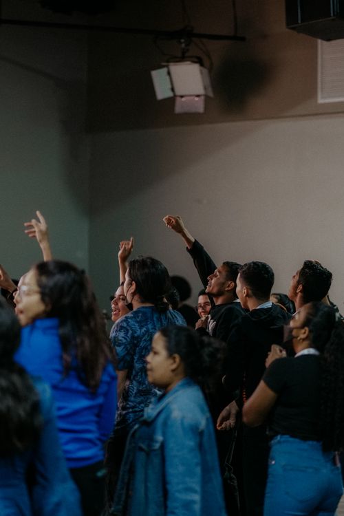 Free A group of diverse people raising hands in a spiritual worship gathering indoors. Stock Photo
