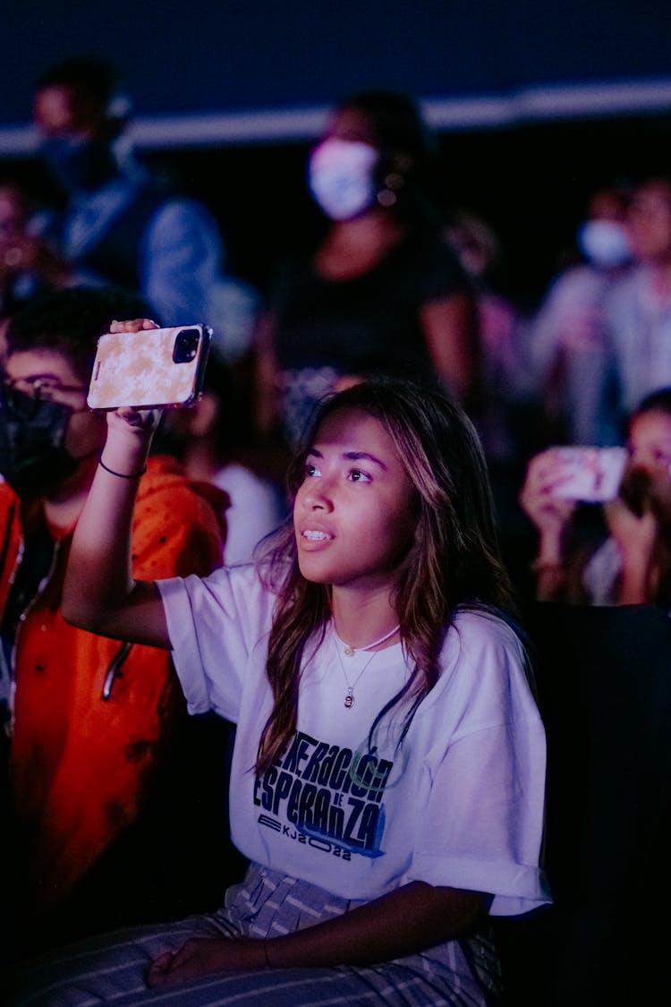 Girl Holding Up A Phone At A Concert 