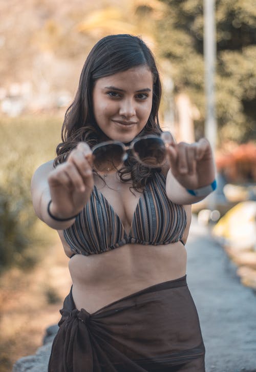 A Woman in Striped Bikini Top Holding Sunglasses