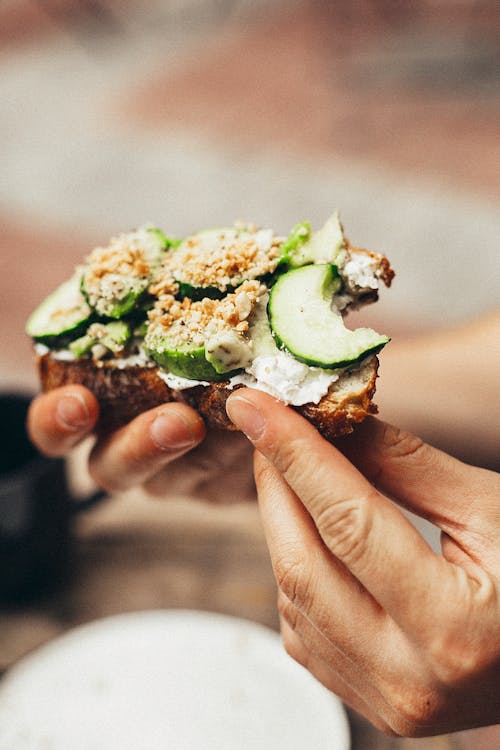 Person Holding Bitten Bread With Green Vegetables