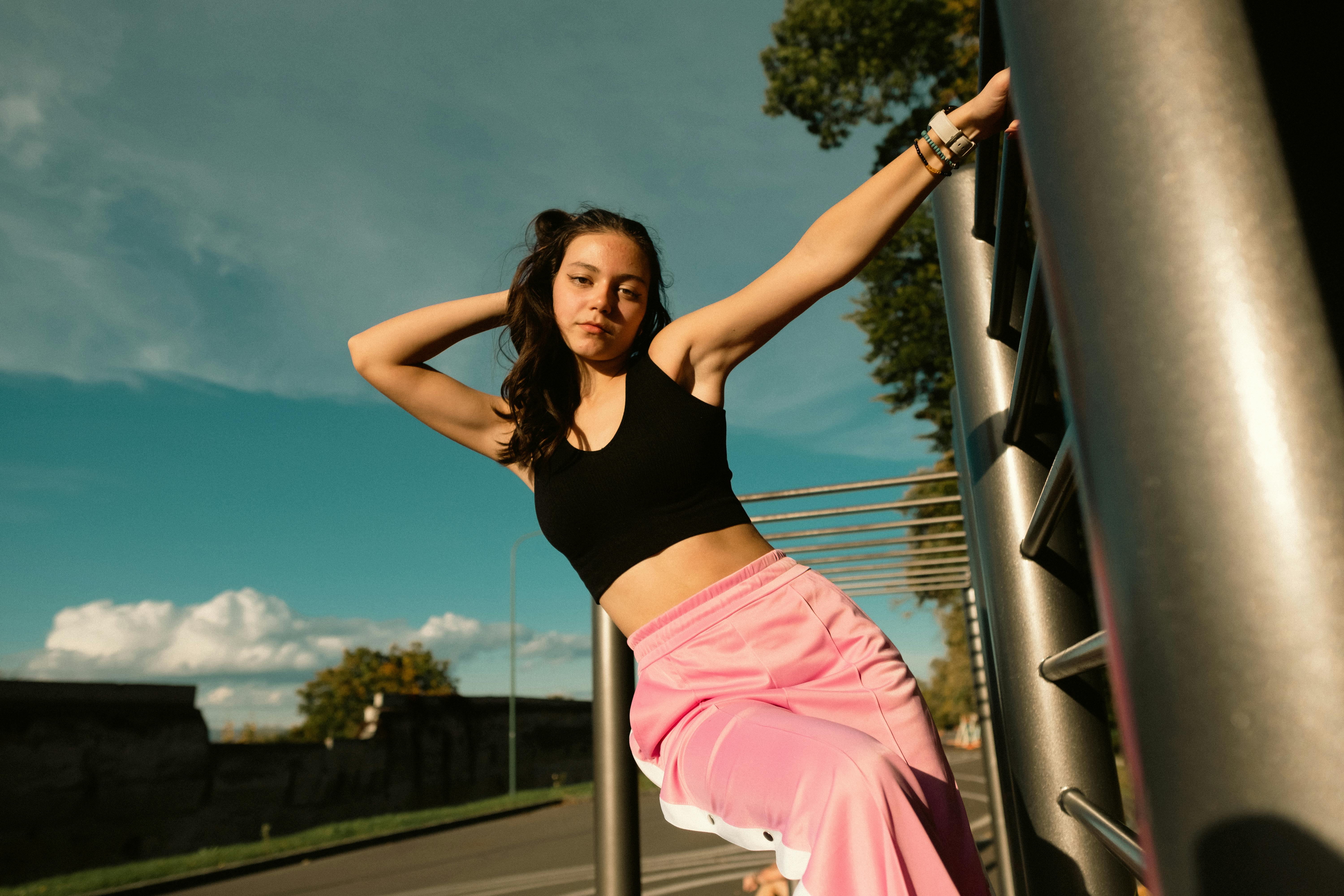 woman in black tank top and pink pants standing on gray metal ladder