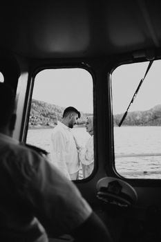 A couple shares a tender moment on deck, seen through a cruise ship's cockpit window.