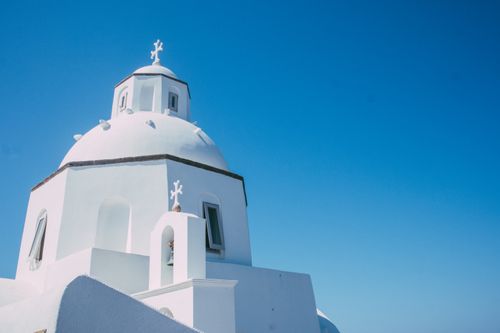 Free Stunning Greek church with white dome contrasting against a clear blue sky, showcasing traditional architecture. Stock Photo