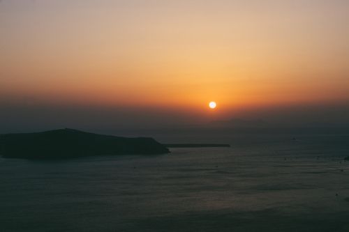 Free A calming view of the sun setting over the ocean, casting warm hues across the sky and sea. Stock Photo