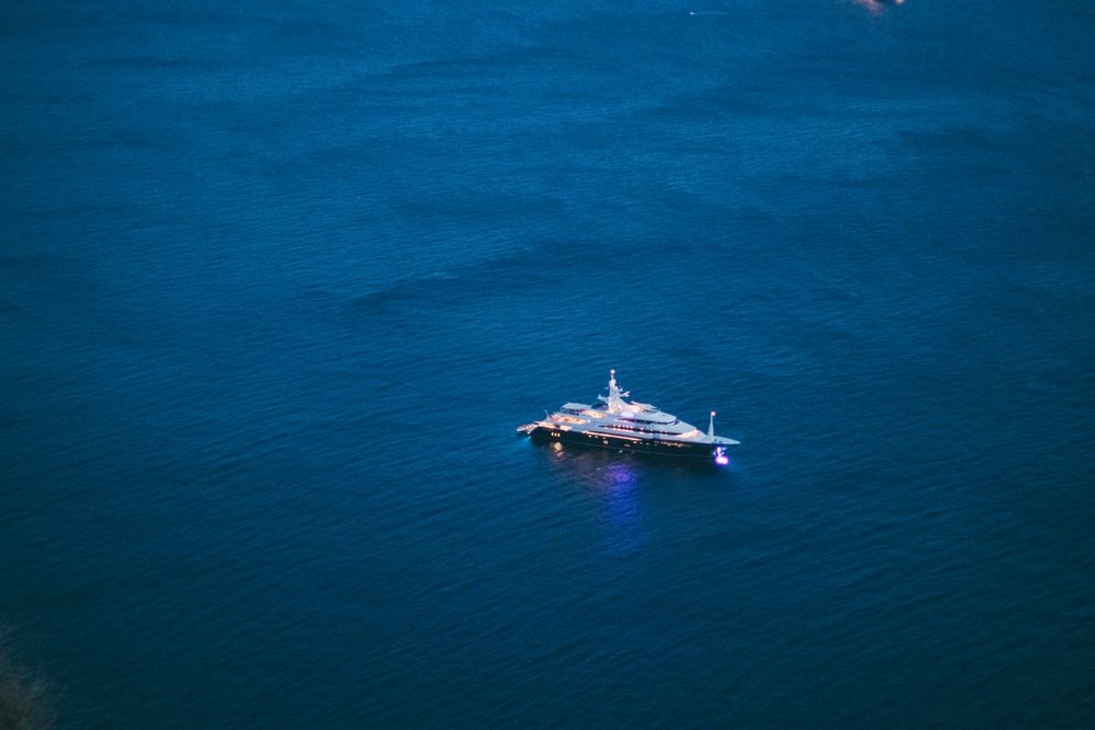 Performance yacht glowing at night on calm open water, seen from above