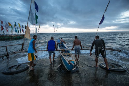 Quatre Personnes Poussant Le Bateau Au Large