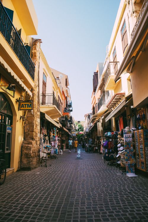 Free Charming narrow street lined with colorful shops and people enjoying a sunny day in town. Stock Photo