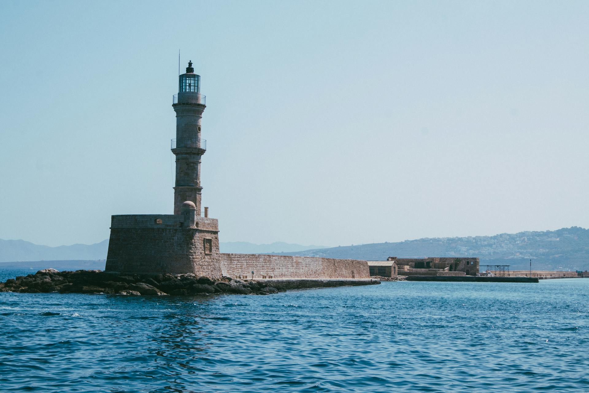 View of the iconic Chania Lighthouse and Venetian Harbor in Crete, Greece on a sunny day.