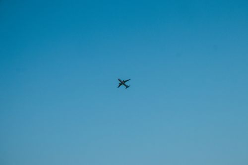 Free An airplane flying high in a clear blue daytime sky, showcasing aviation and freedom. Stock Photo
