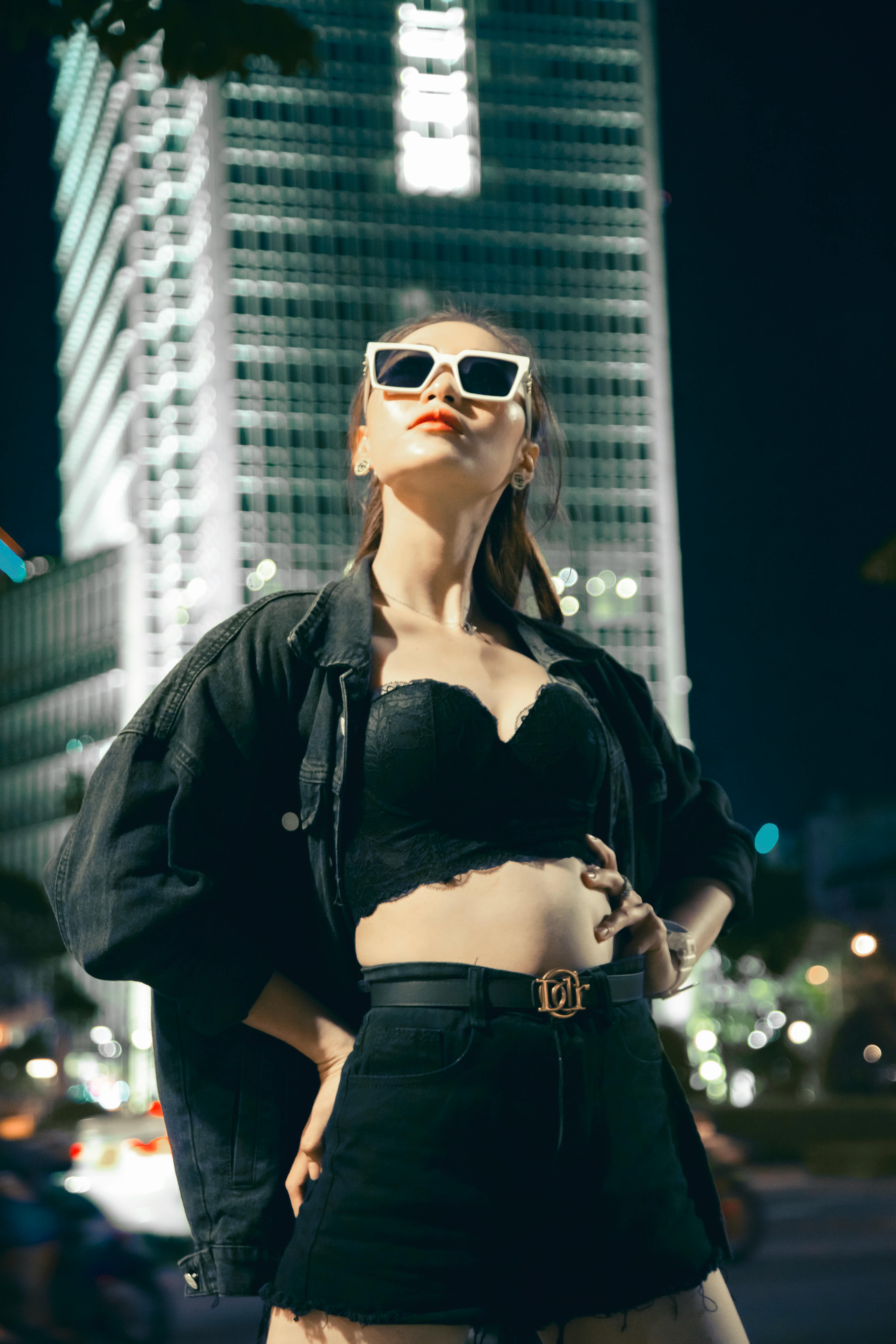 Free Fashionable woman posing confidently at night in cityscape. Modern urban vibe. Stock Photo
