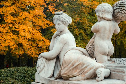 Marble sculpture with autumn foliage background in a serene park setting.
