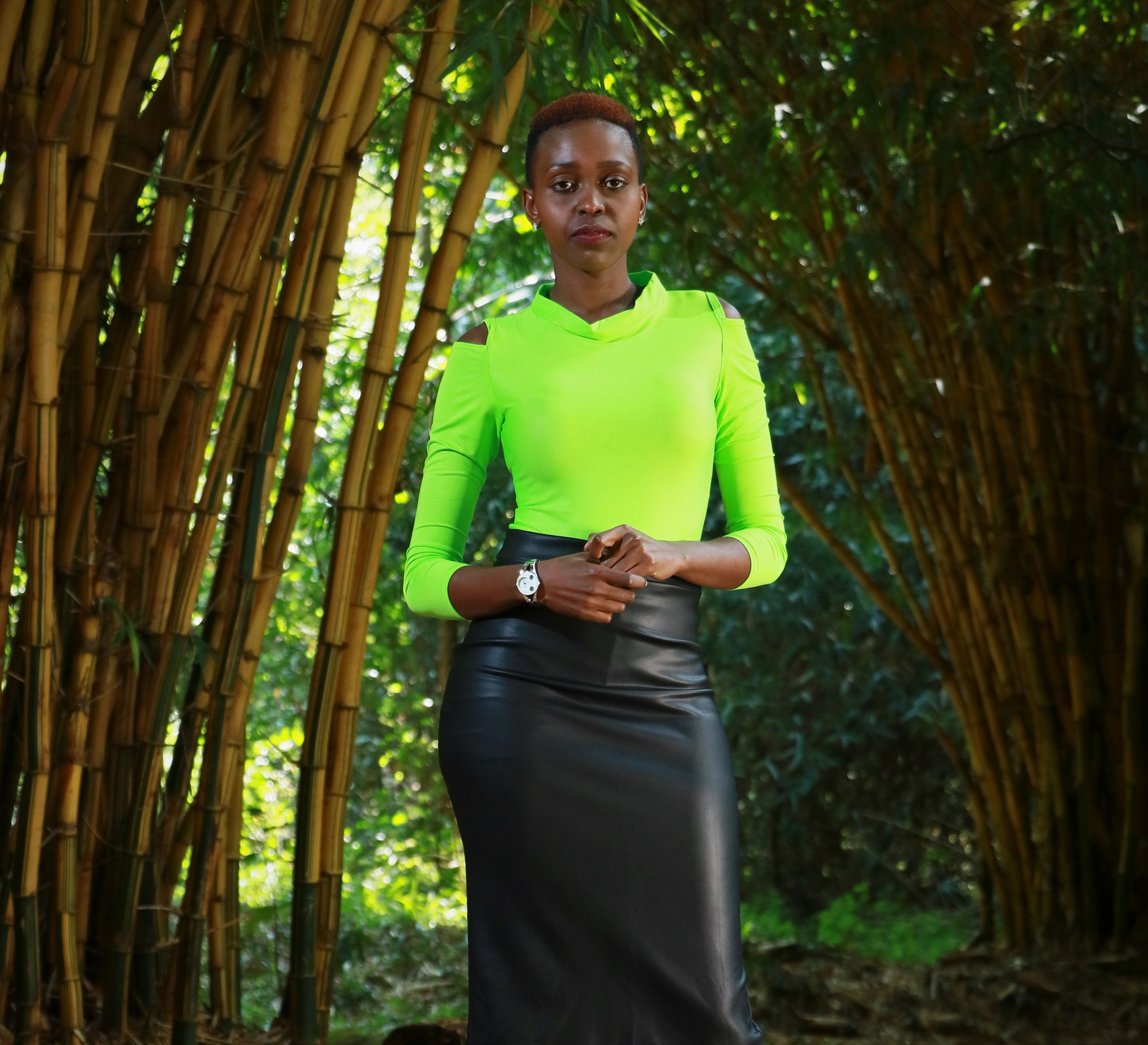 Stylish woman posing in a vibrant outfit surrounded by bamboo in Nairobi.