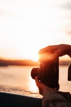 Silhouette of a camera capturing a breathtaking sunset over the water.