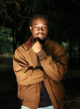 一位穿着棕色夹克的自信男子在树木背景下的户外肖像