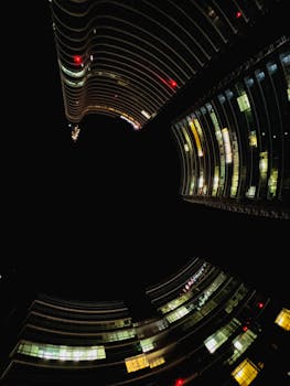 A striking upward view of modern skyscrapers against a night sky, showcasing architectural design.