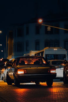 A vibrant city street captured at night featuring illuminated vehicles and bustling traffic.