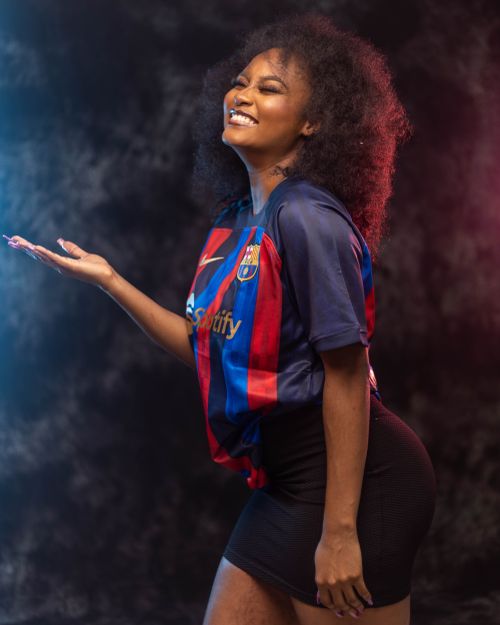 Free A joyful woman with afro hair posing confidently indoors wearing a soccer jersey. Stock Photo