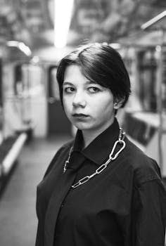 Black and white portrait of a woman with a serious expression on a train.