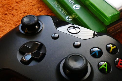 Pengontrol Xbox One Di Samping Tiga Kotak Xbox One