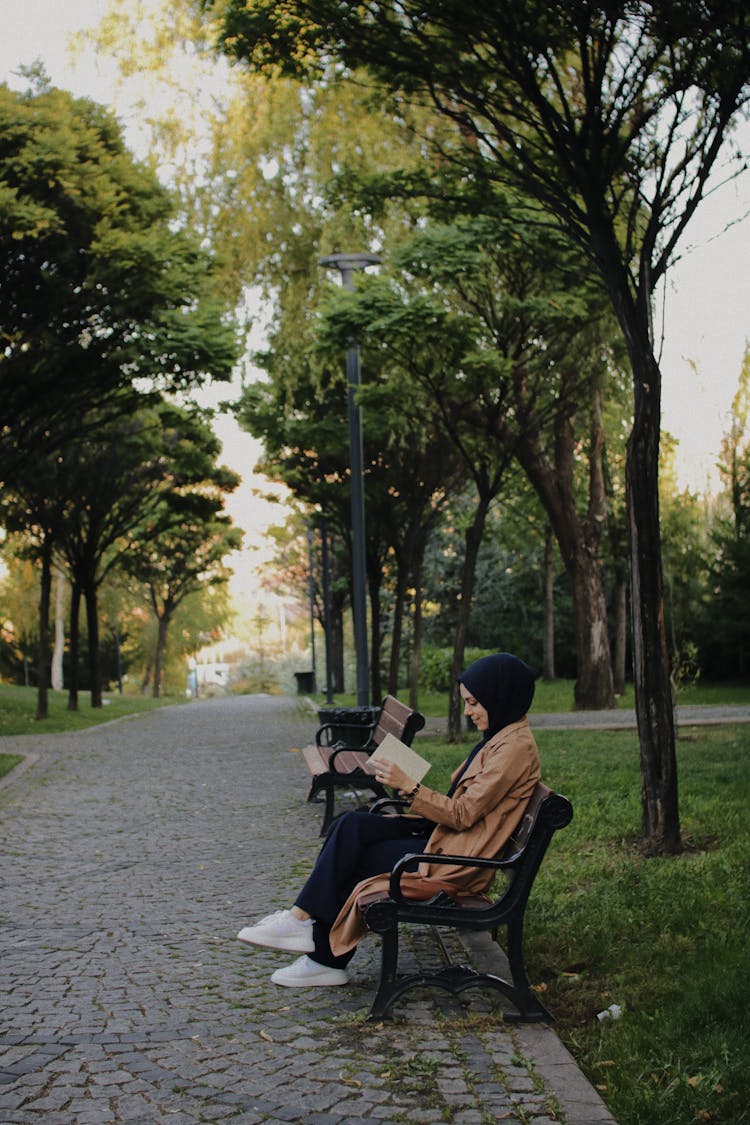 Woman Sitting On A Bench In Park And Reading A Book 