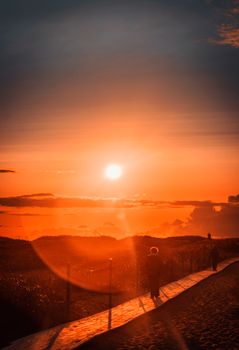 Golden sunset over a beachfront pathway with silhouettes in tranquil scenery. Ideal for travel and nature themes.