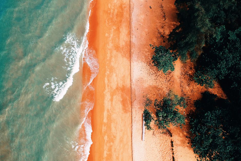 A stunning aerial view showcasing vibrant beach sands, lush greenery, and ocean waves.