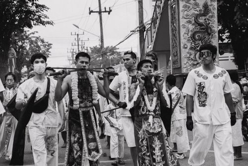 Free Men in traditional costumes participate in a vibrant street festival parade with cheek piercings. Stock Photo