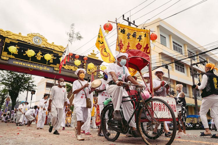 Men Riding Bike On Street During City Festival