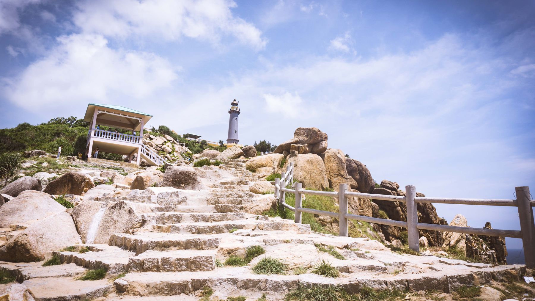 Explore the rugged beauty and historical lighthouse along a rocky hill path in Phu Yen, Vietnam.