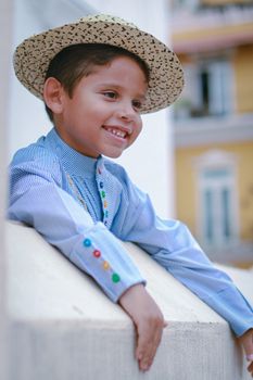 Cheerful boy with a straw hat leaning on a rail outdoors