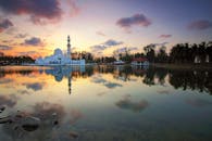 日落时分，平静的湖面倒映着美丽的清真寺，四周环绕着郁郁葱葱的自然风光