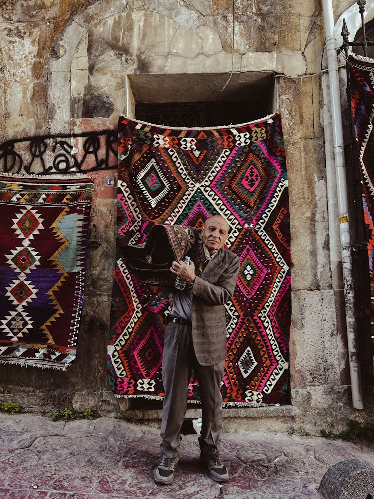 Man In A Suit Standing And Holding A Rug