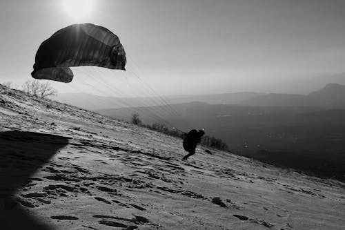 Man Skiing down the Mountain Slope with a Parachute 