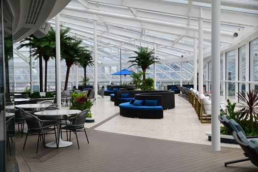Bright indoor leisure area featuring stylish seating, glass roof, and lush plants.