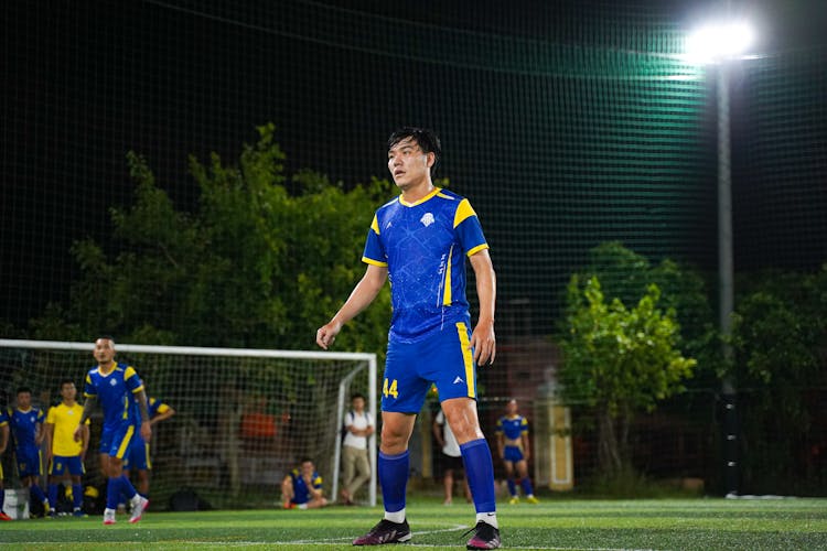 Man In Blue And Yellow Soccer Jersey Standing On The Soccer Field