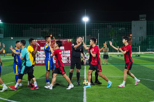 Free Players and referee exchanging handshakes after a soccer match under stadium lights. Stock Photo