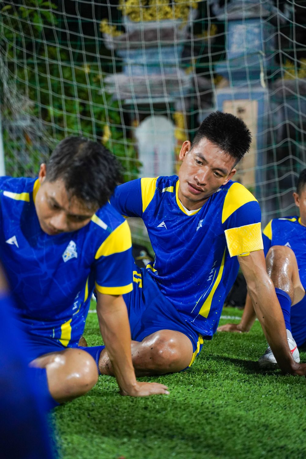 Academy players in coordinated training uniforms stretching together on a sports field