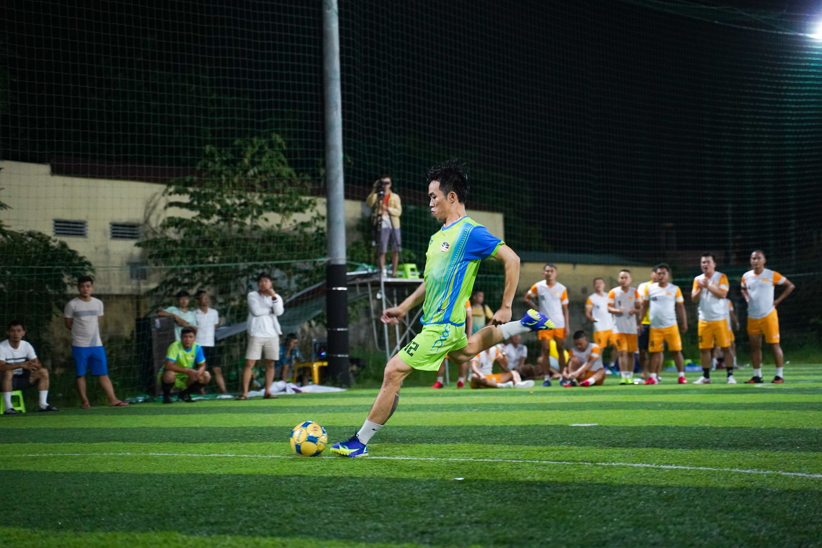 Football player striking the ball on an artificial turf pitch