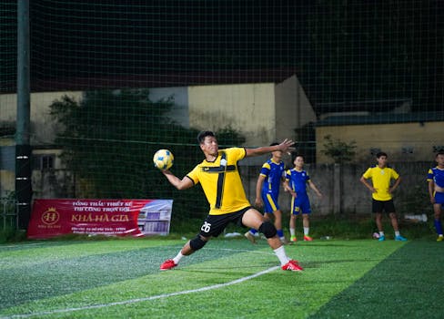 Dynamic soccer match at night with an athlete in action throwing the ball on the field.