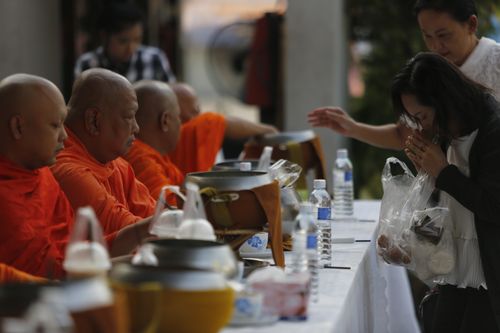 Free Monks receiving alms during a traditional ceremony outdoors, featuring people in prayer. Stock Photo
