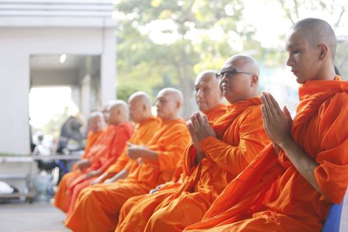 Free A group of Buddhist monks in orange robes meditating outdoors, embodying spirituality and tranquility. Stock Photo