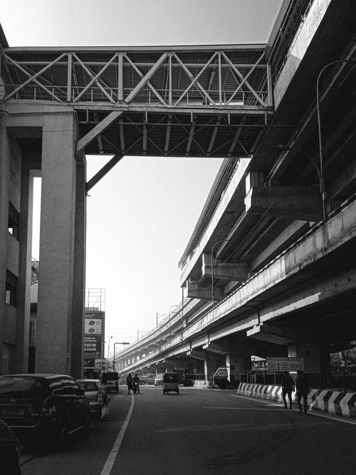 Free Dramatic black and white image of a busy urban overpass with flowing traffic and towering architecture. Stock Photo