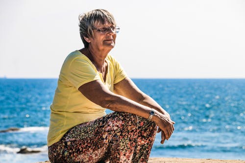 Free Woman Sitting on Beach Shore Stock Photo