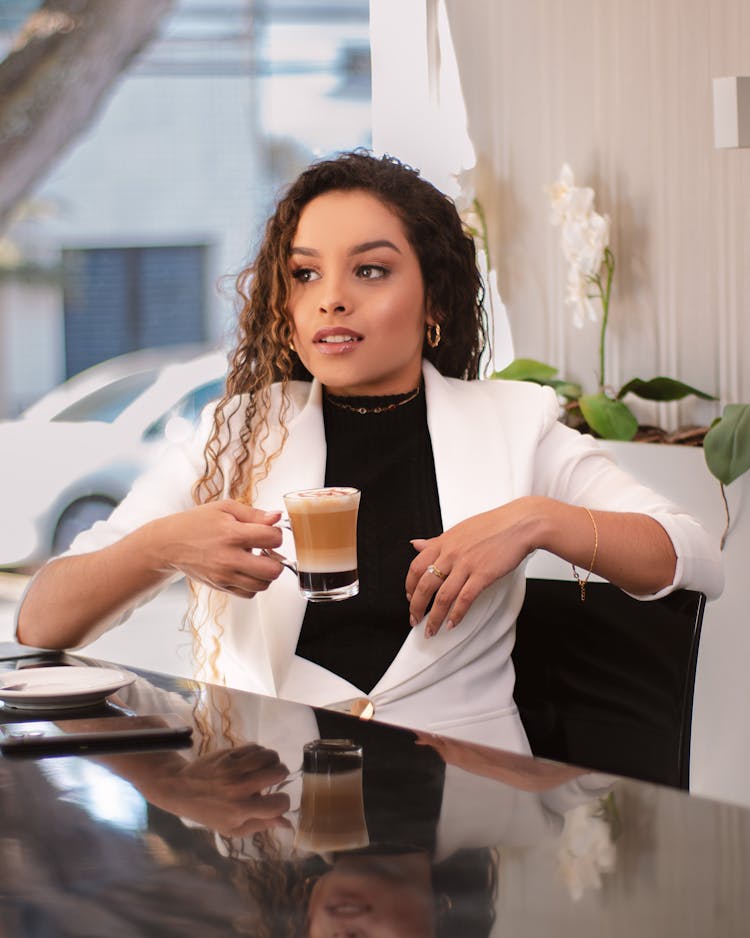 A Woman In White Blazer Holding A Cup Of Coffee